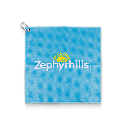 Blue golf towel with "Zephyrhills 1964" logo in the center, metal ring and hook in the top left corner, and black trim at the bottom.